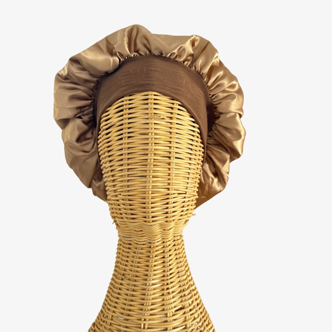 Ratan Mannequin head with a golden brown satin bonnet on a white background